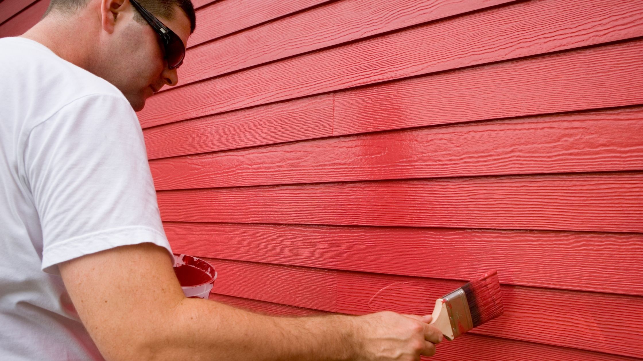 一个人在粉刷红房子